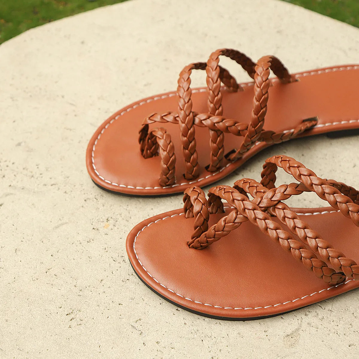 Women's white woven clip-toe flat sandals with a rubber sole on a plain background.