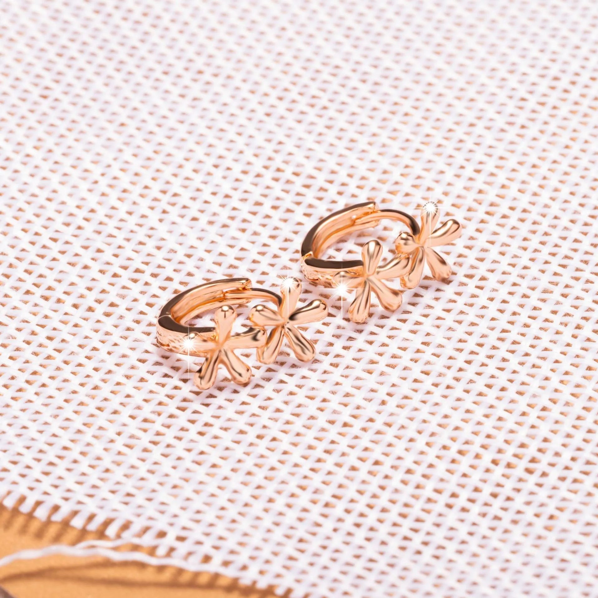 Rose gold circular earrings with a waterdrop flower design on a white background.