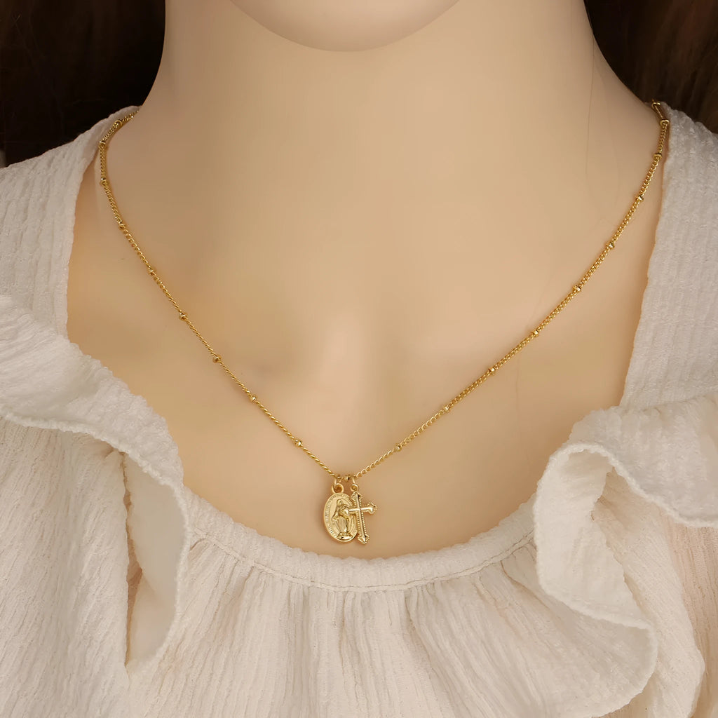 Gold geometric cross Virgin Mary pendant necklace on a chain.