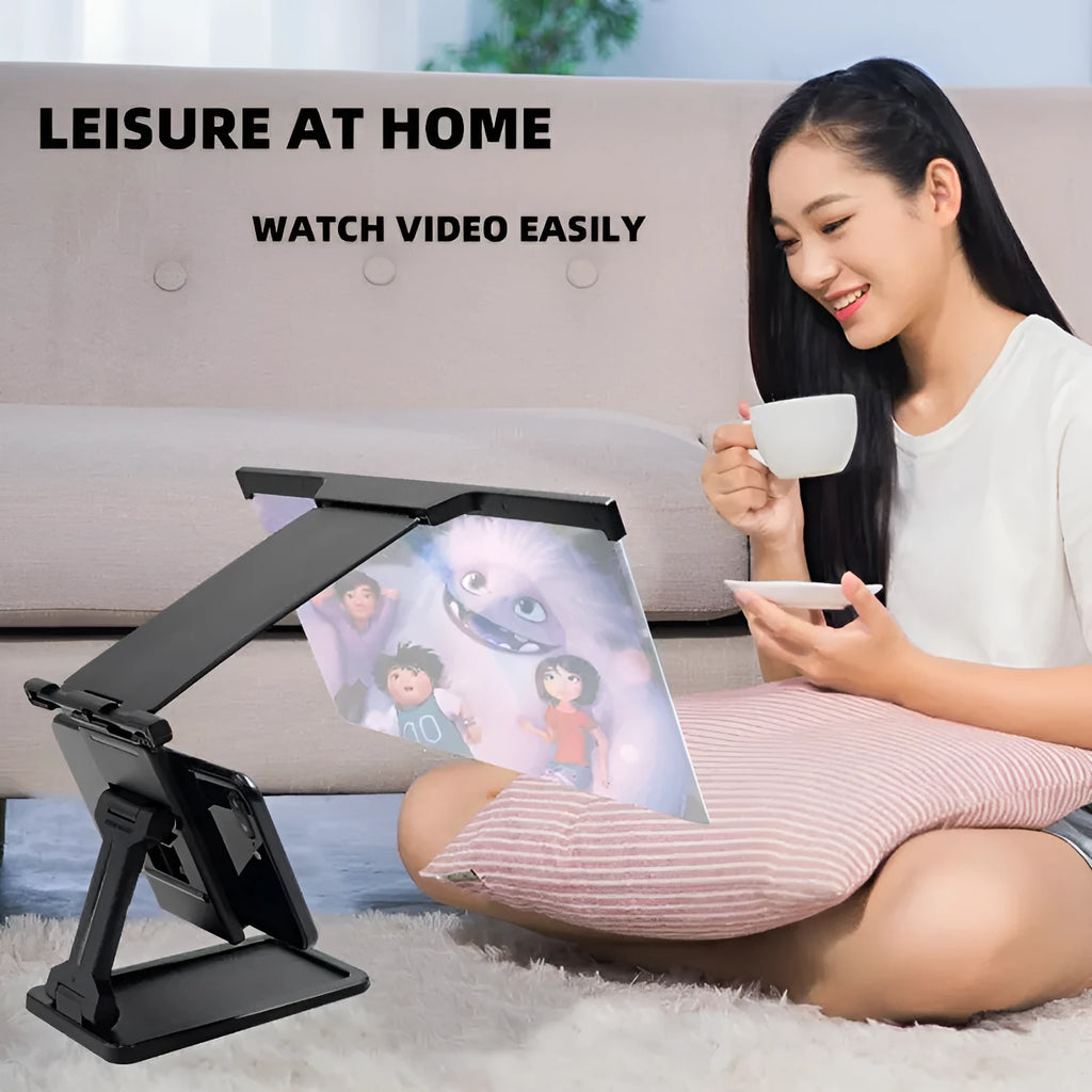Black foldable mobile phone screen magnifier with a detachable phone holder on a desk.
