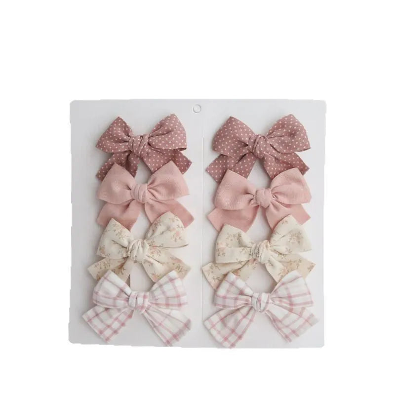 Children's fabric dovetail bow hairclips set showing multiple colour and pattern options