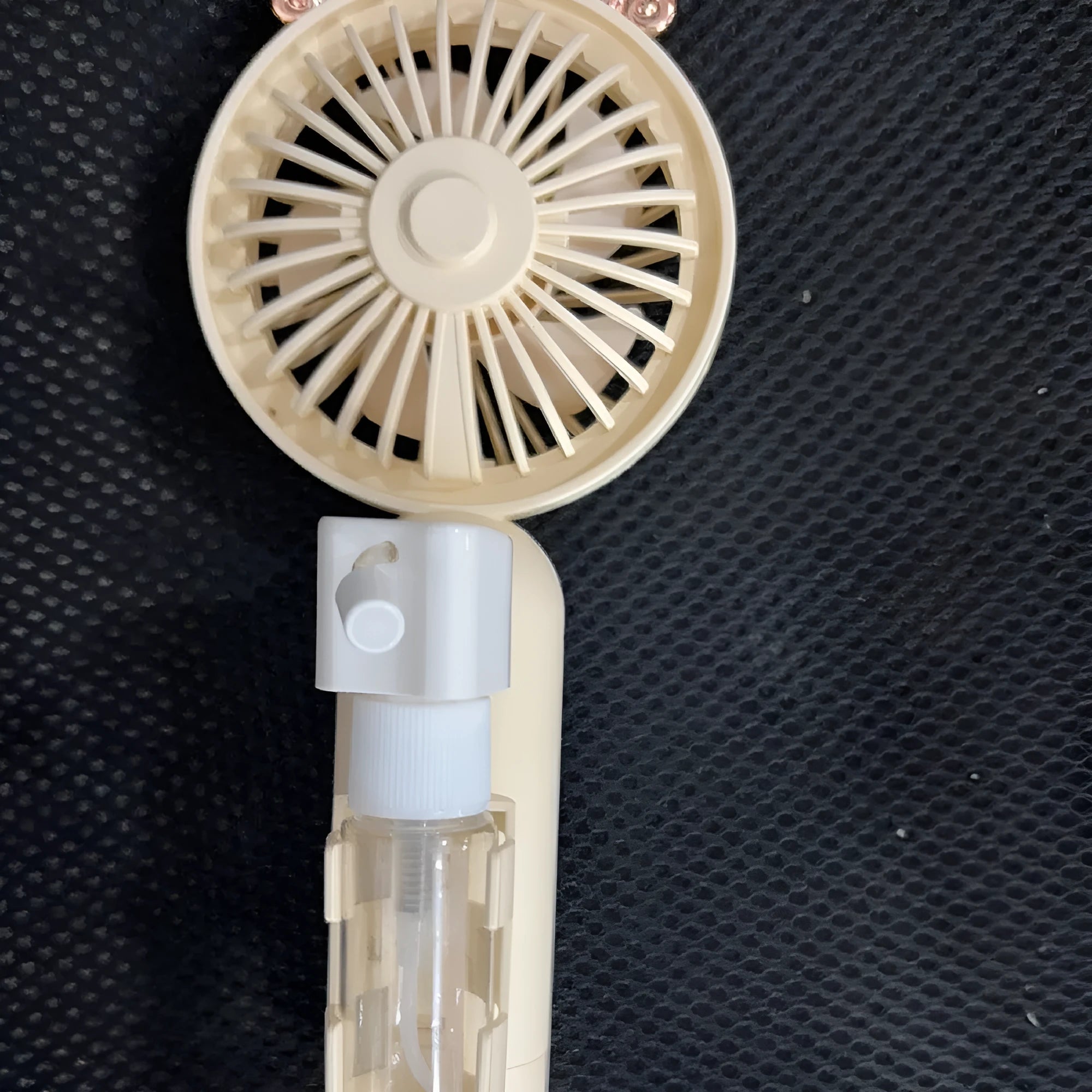 Plastic USB rechargeable nozzle fan in apricot colour on a desk.