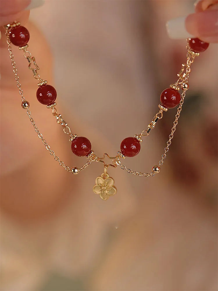 Red agate double layer bracelet with floral and peach blossom detailing on woman's wrist