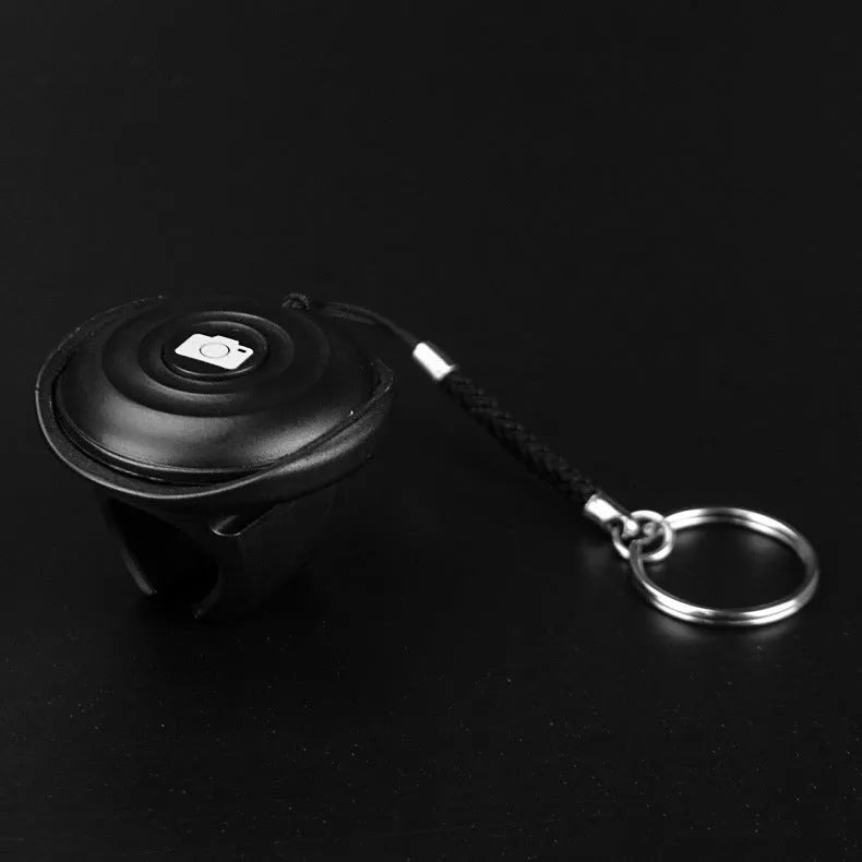 Black Bluetooth remote control for smartphone selfies and camera shutter.