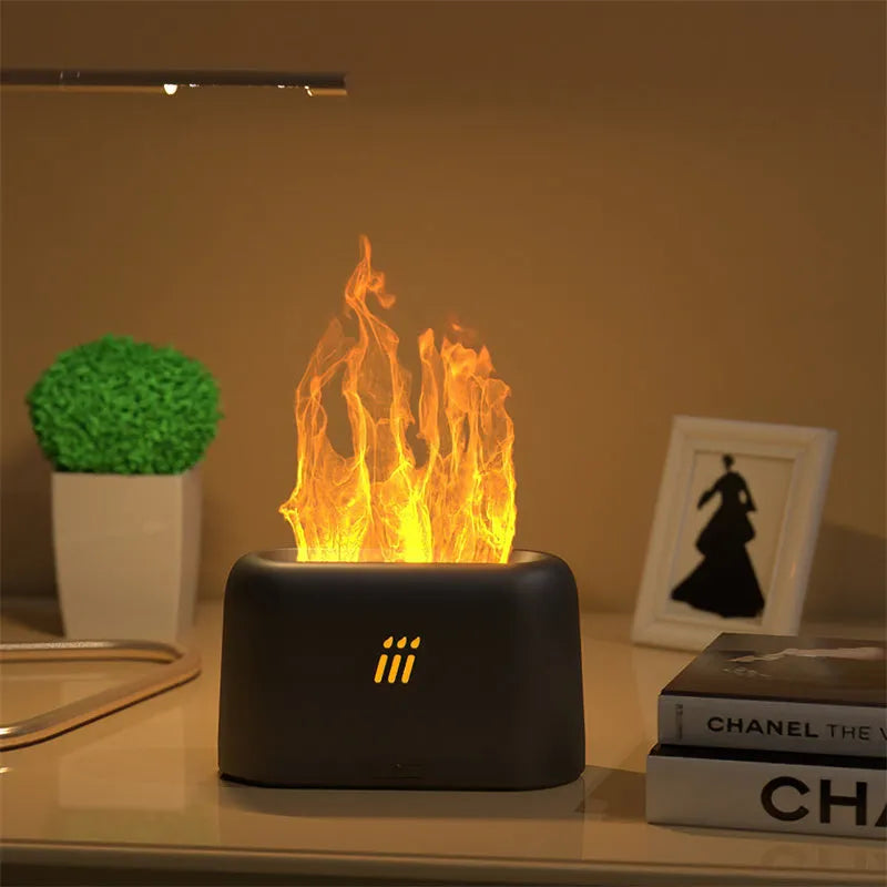 Black and white flame aroma diffuser humidifier with LED lights and remote control on a table.