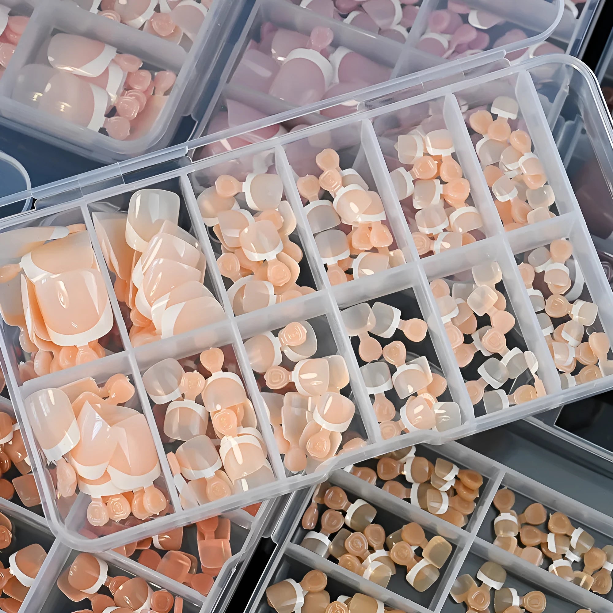120 piece set of nude French white tip artificial toenails in nine shades, showing square short shape.