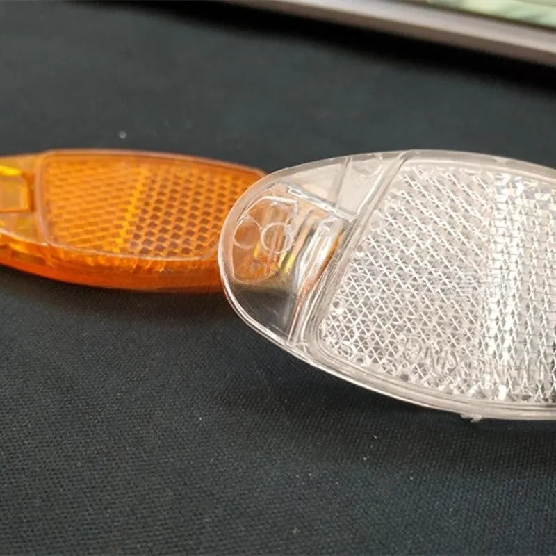 Bicycle spoke reflector decoration in white or yellow measuring 7.2cm by 3.5cm