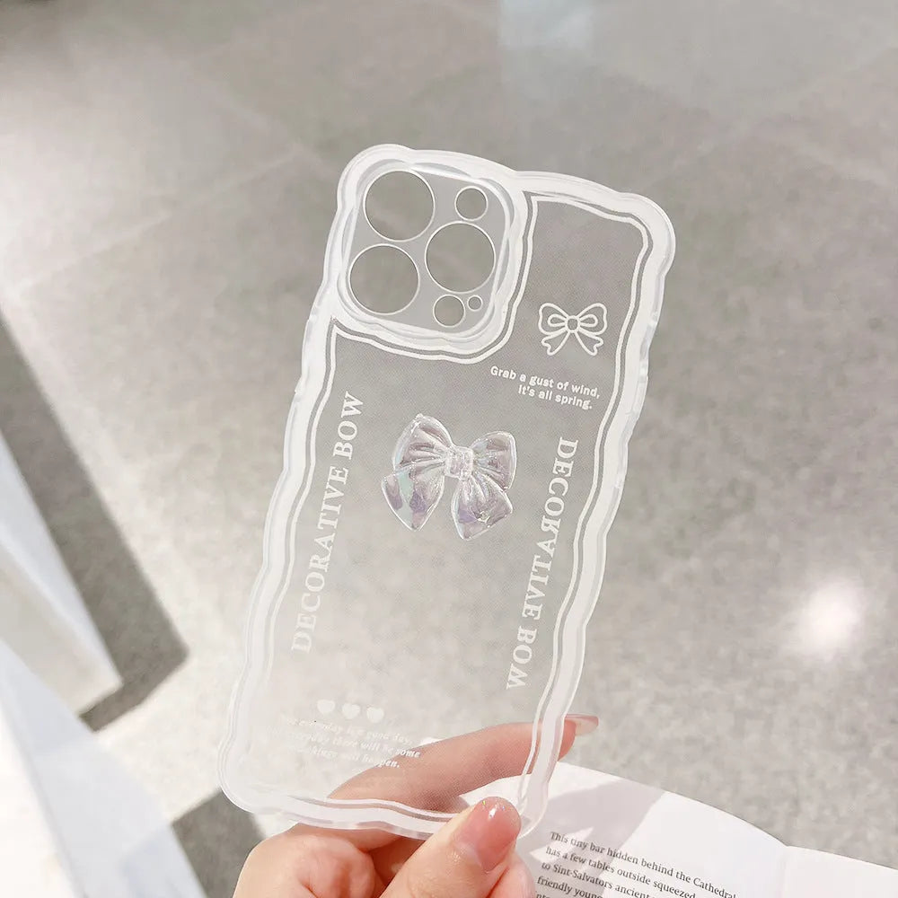 Clear iPhone case with a raised 3D bow design and a white love lanyard on a table.