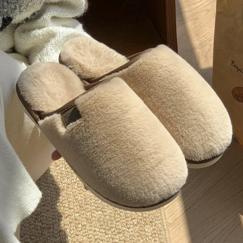 A pair of solid colour winter plush slippers with a PVC sole on a wooden floor.