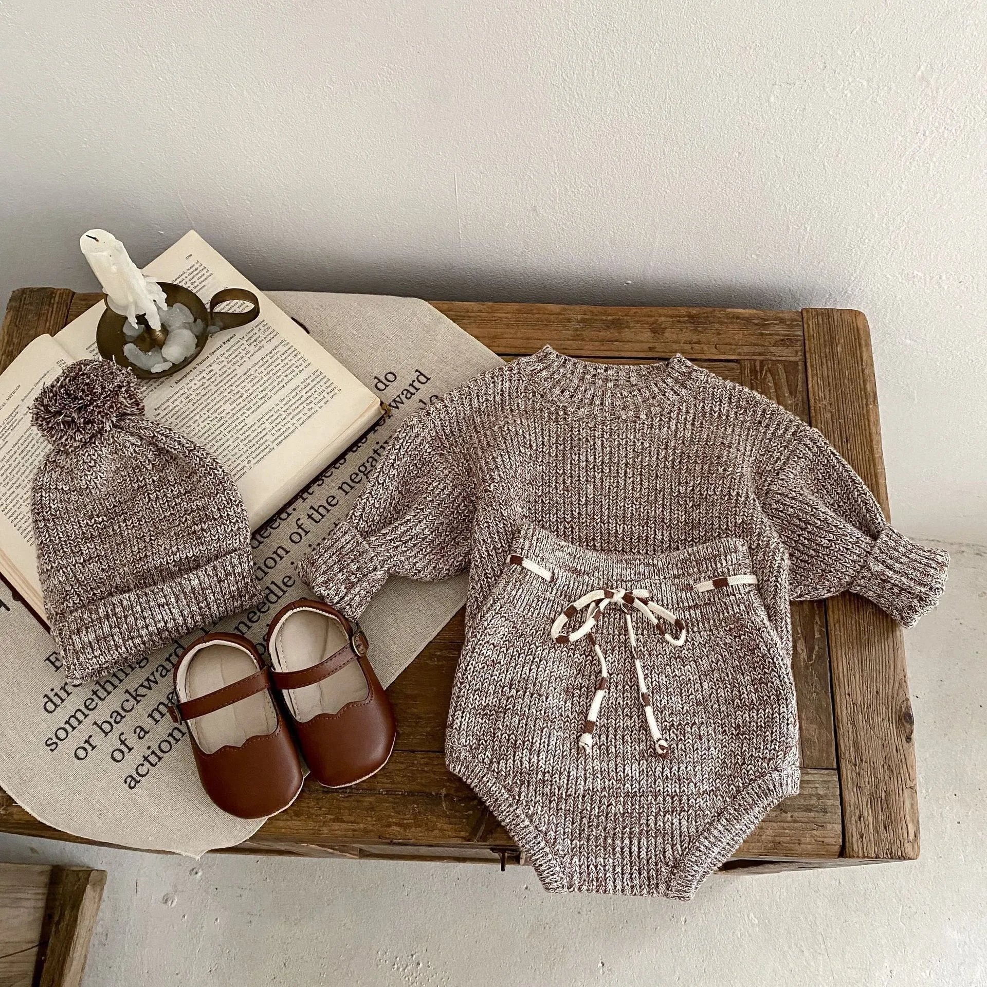 Dark brown knitted 3-piece set for infant girl with pullover blouse, pants, and fur ball hat