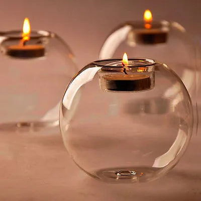 Clear round handmade hollow glass candle holder sphere on a table.