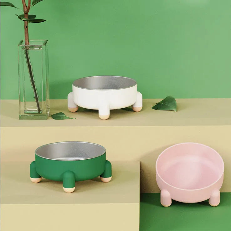 A green stainless steel pet bowl with a non-slip base and high foot, placed on a floor.