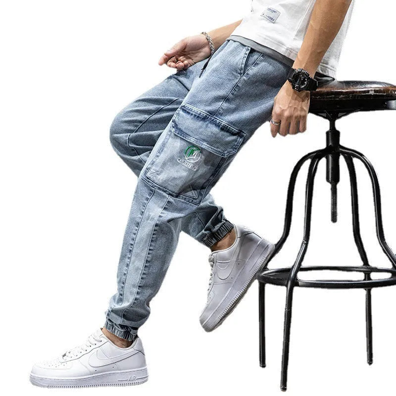 Man wearing loose straight leg cargo jeans in blue, showing mid waist and zipper fly detail.