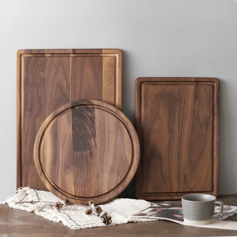Solid black walnut wood chopping board with a deep perimeter groove and a side handle, shown as a serving tray.