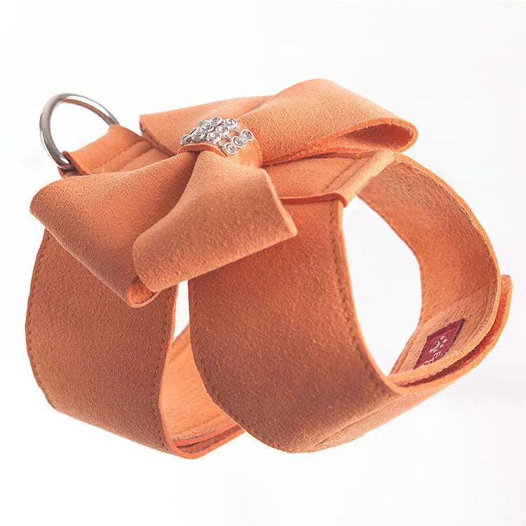 A pink dog harness with a white bowknot on the chest strap, shown on a small dog.