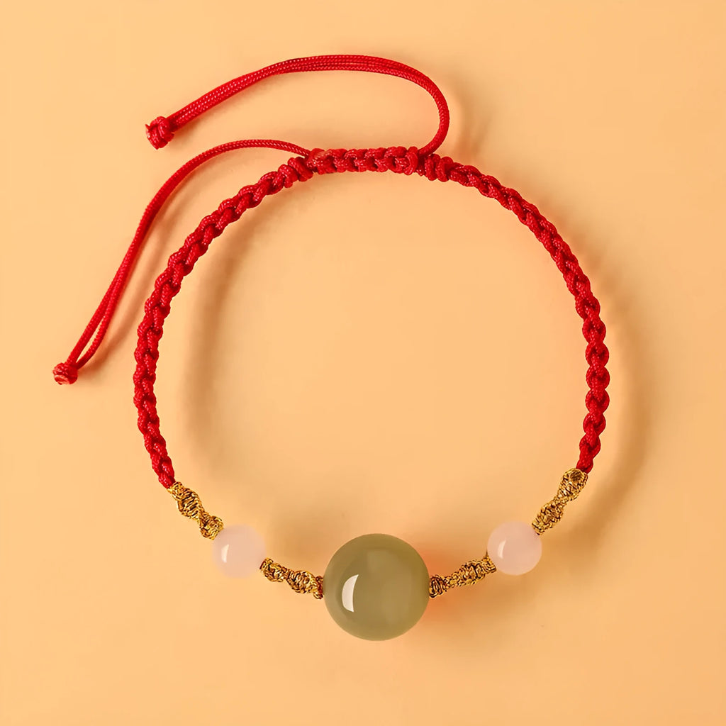 Hand-woven red rope bracelet with Hetian jade lucky charm beads on a model's wrist.