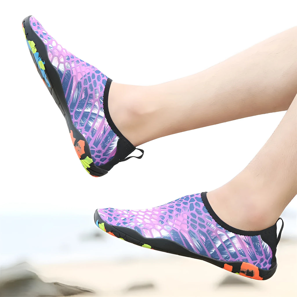 Blue and black Lycra fabric beach wading shoes with EVA foam soles on a sandy background.