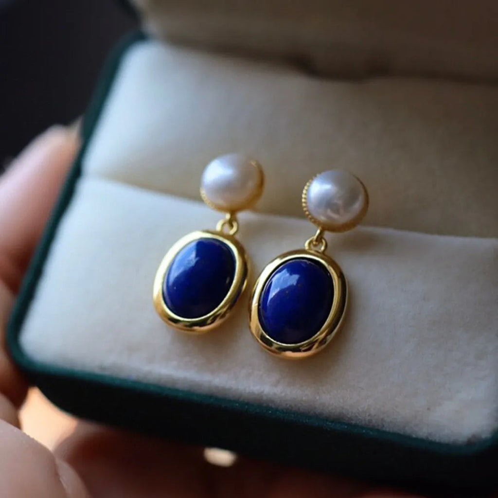 A pair of simple silver earrings with blue lapis lazuli pearls and auspicious pattern details.