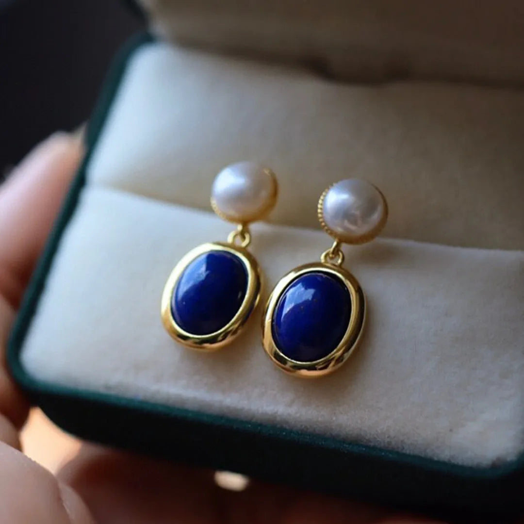 A pair of simple silver earrings with blue lapis lazuli pearls and auspicious pattern details.