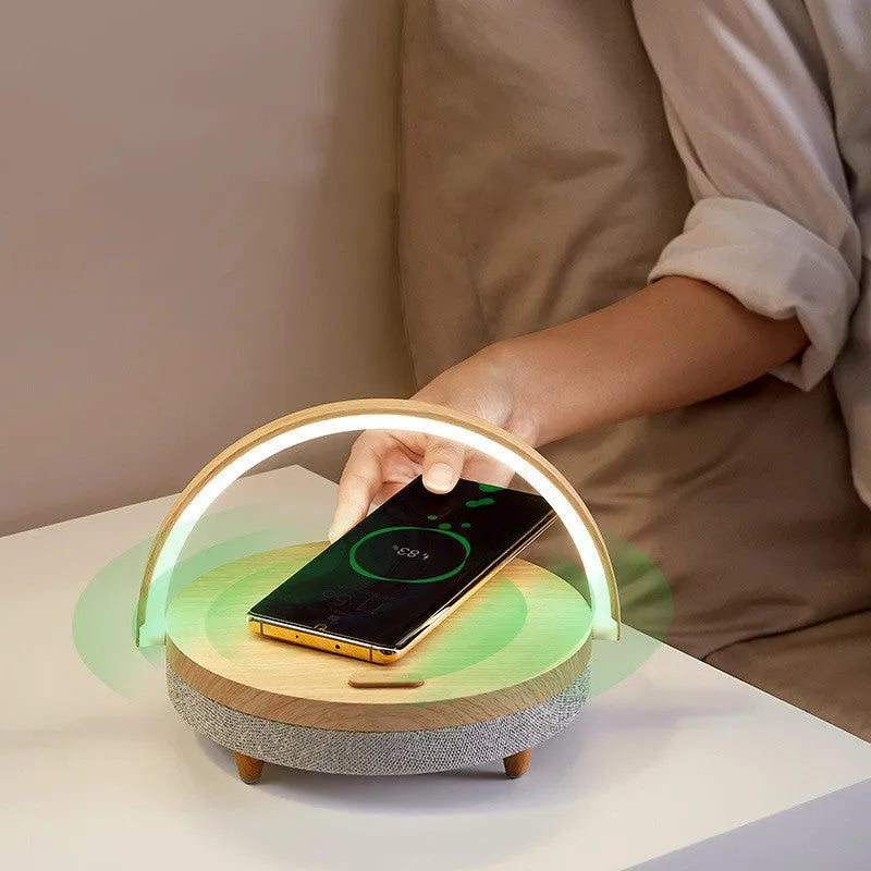 White wireless charging Bluetooth speaker and LED night light unit with phone holder on marble pattern base.