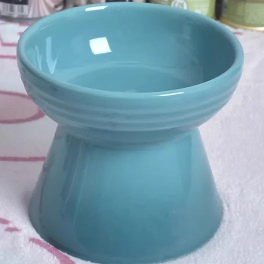 A black ceramic pet bowl with a chin-high foot and a choice of flat or slanted rim.