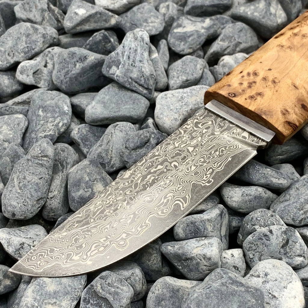 White Shadow Damascus steel short knife with Thuja wood handle, showing blade pattern.