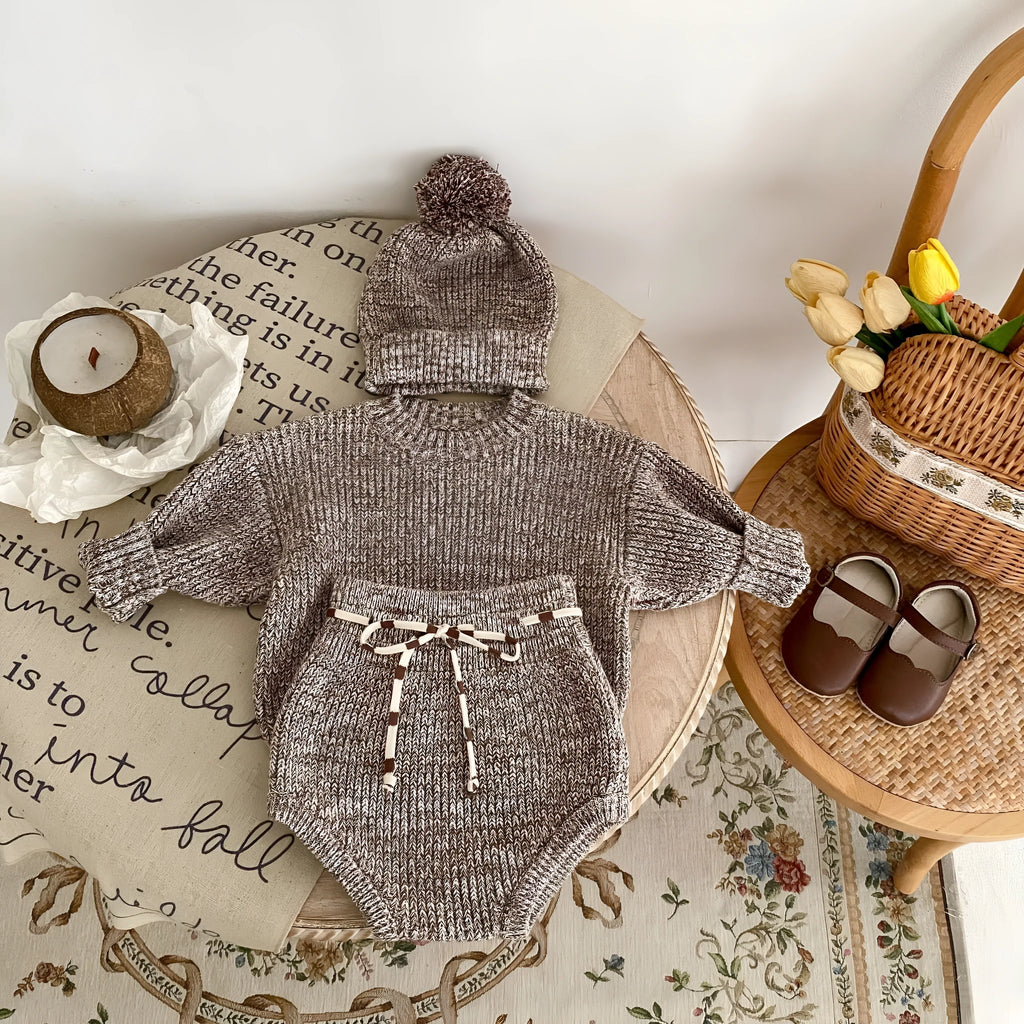 Dark brown knitted 3-piece set for infant girl with pullover blouse, pants, and fur ball hat