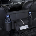 Black leather car seat hanging storage organiser for tissue boxes, shown between vehicle front seats.