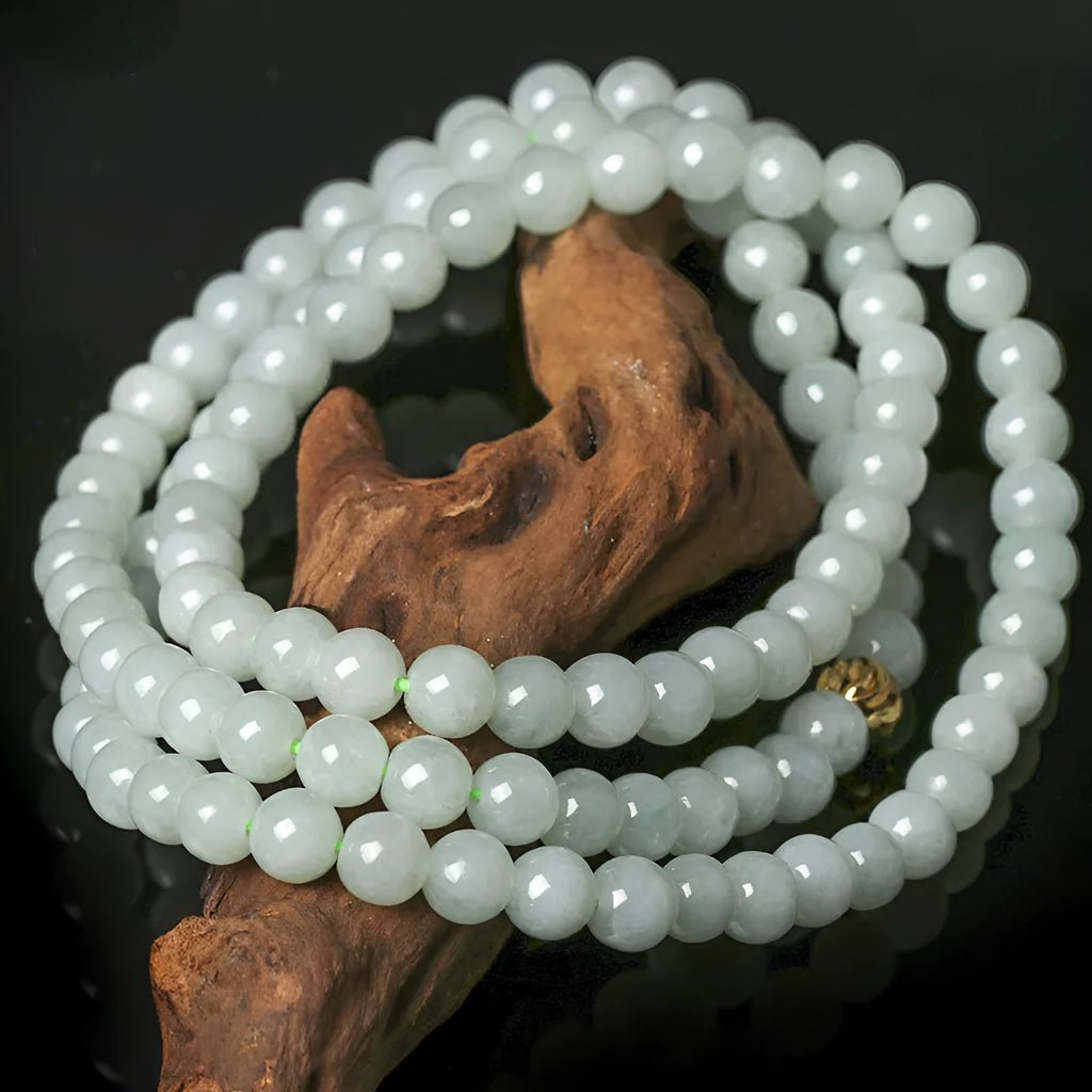 Close-up of a women's adjustable necklace with round white and green natural jade beads on a metal chain.
