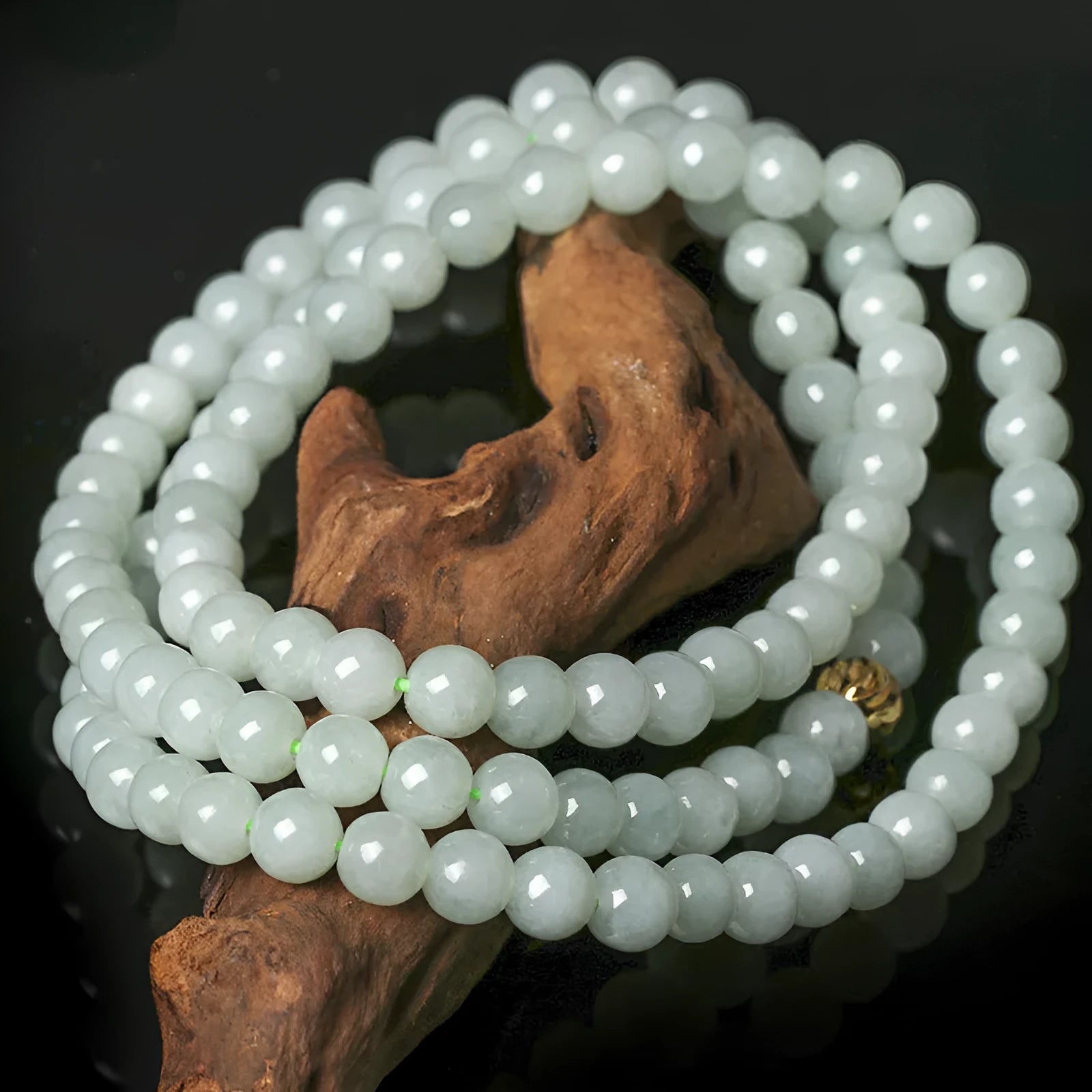 Close-up of a women's adjustable necklace with round white and green natural jade beads on a metal chain.