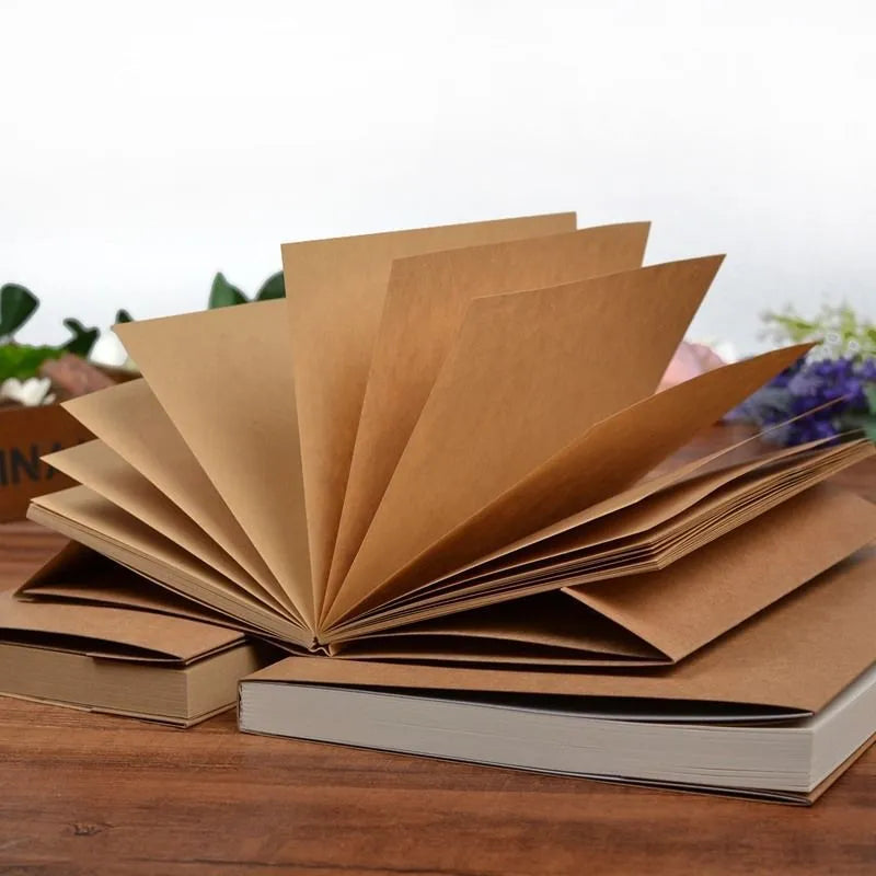 Brown kraft paper sketchbook open on a table, showing its wireless binding and 16K page size.