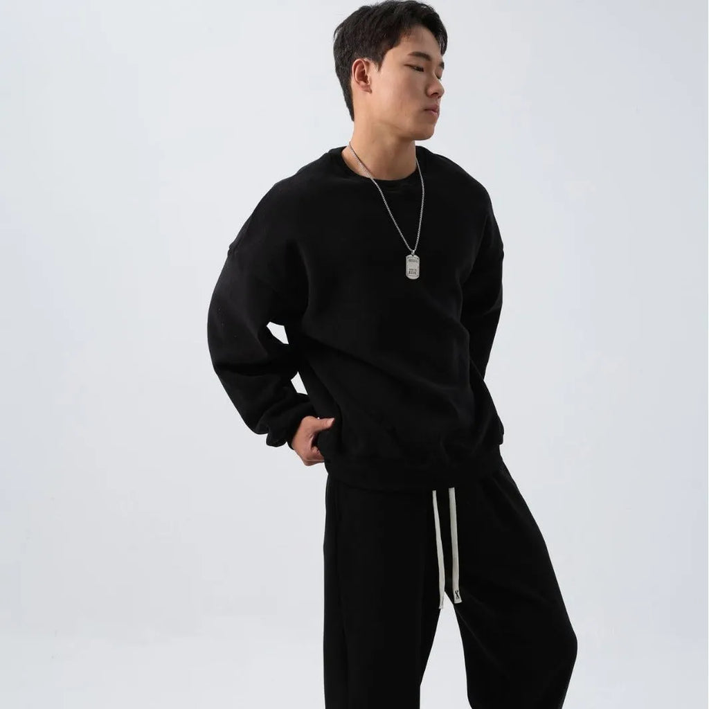 Man wearing a black polar fleece sports suit with a crew neck coat and loose trousers.