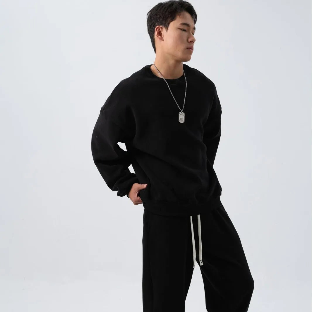 Man wearing a black polar fleece sports suit with a crew neck coat and loose trousers.