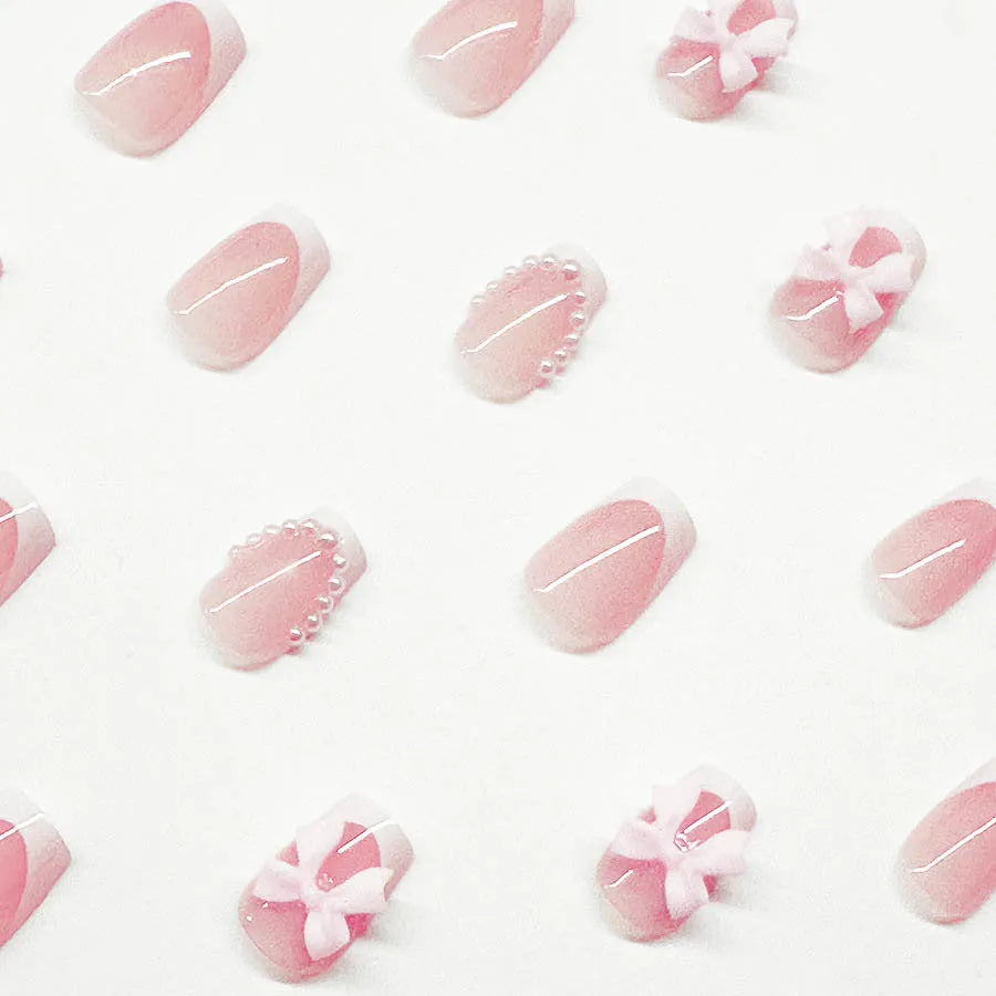 Short artificial French manicure nails with white bow, tulip, and starry sky designs on a square tip.