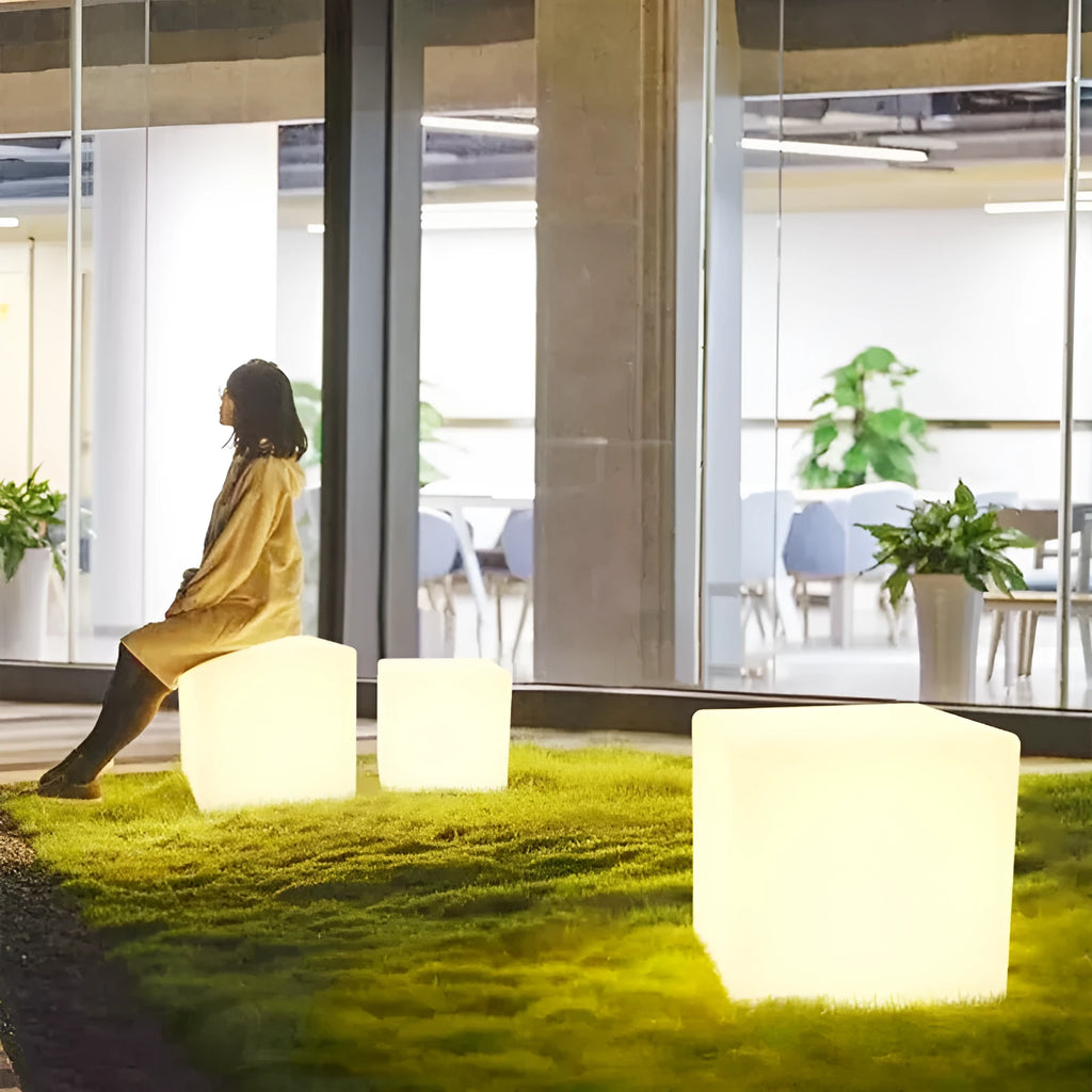 White square LED cube stool light on patio, modern outdoor seating with integrated lighting.