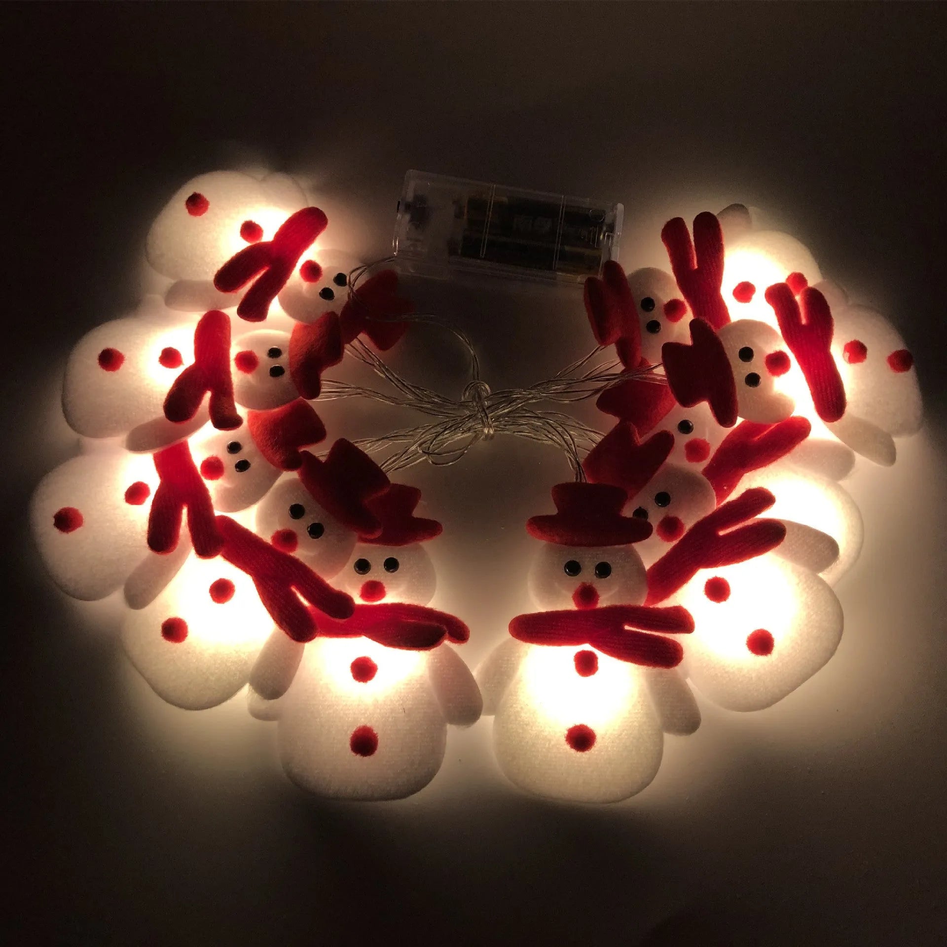 Snowman and elk deer decorative LED Christmas string lights glowing warm white on a green garland.