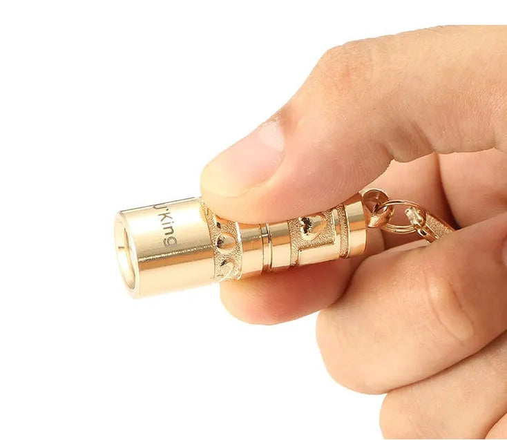 Gold electroplated zinc alloy portable LED keychain flashlight for outdoor emergency use.