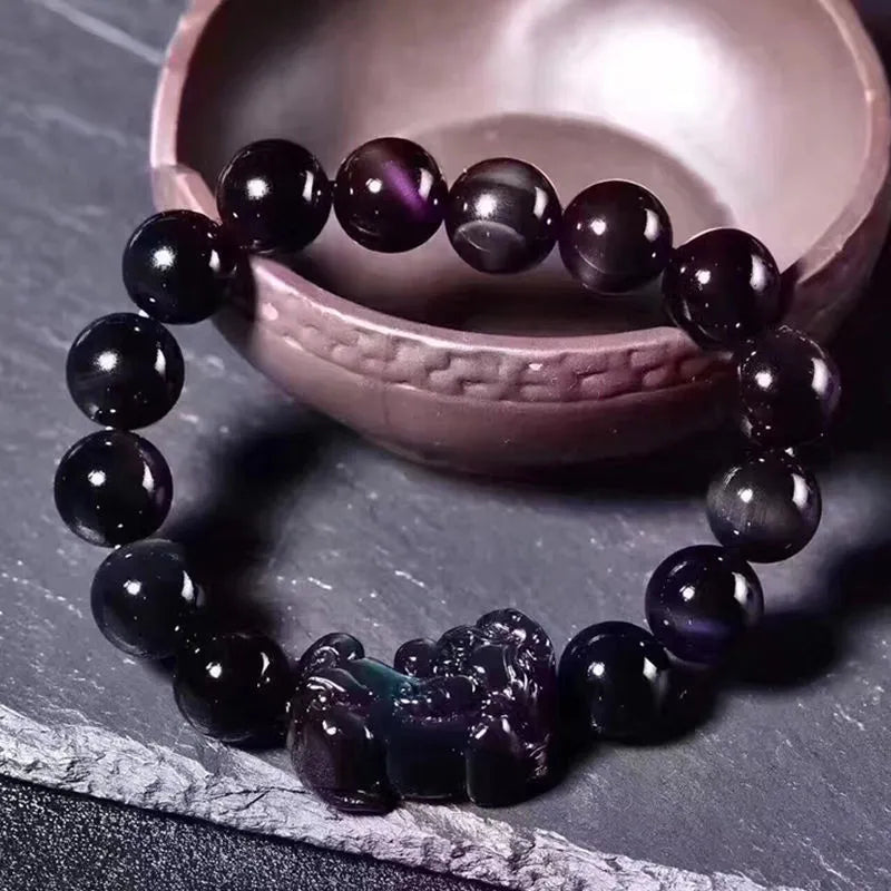 Natural eye obsidian crystal bracelet with ice colour tones and silver clasp on a wrist.
