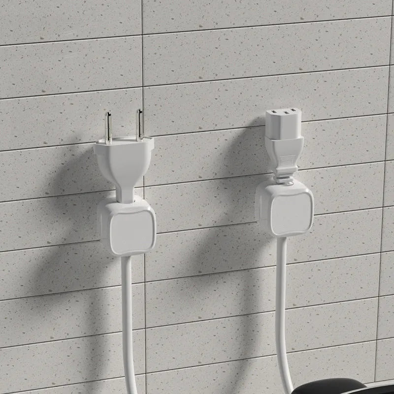 White and black magnetic cable clips with adhesive backing holding a USB cable against a wooden desk edge.