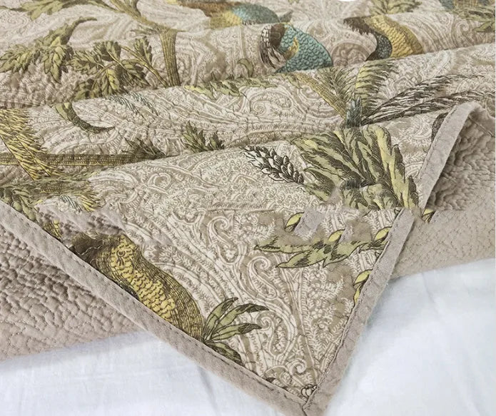 Blue American-style floral and bird quilted cotton bedspread set on a bed, showing its 230x250 cm size.