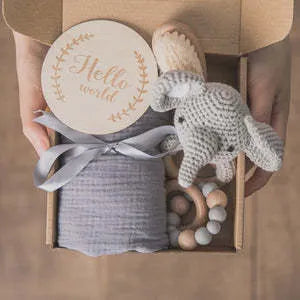 Baby teething toy gift set with bamboo blend gauze blanket, wooden beech bell, teether, brush, and milestone marker.