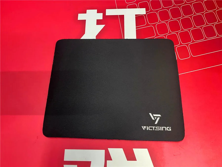 Black rectangular rubber gaming mouse pad on a wooden desk