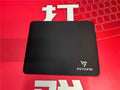 Black rectangular rubber gaming mouse pad on a wooden desk