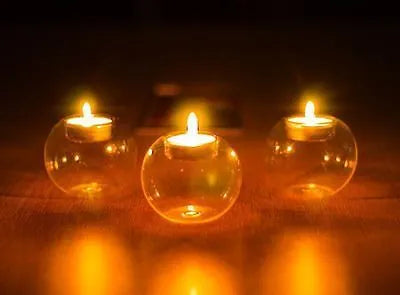 Clear round handmade hollow glass candle holder sphere on a table.