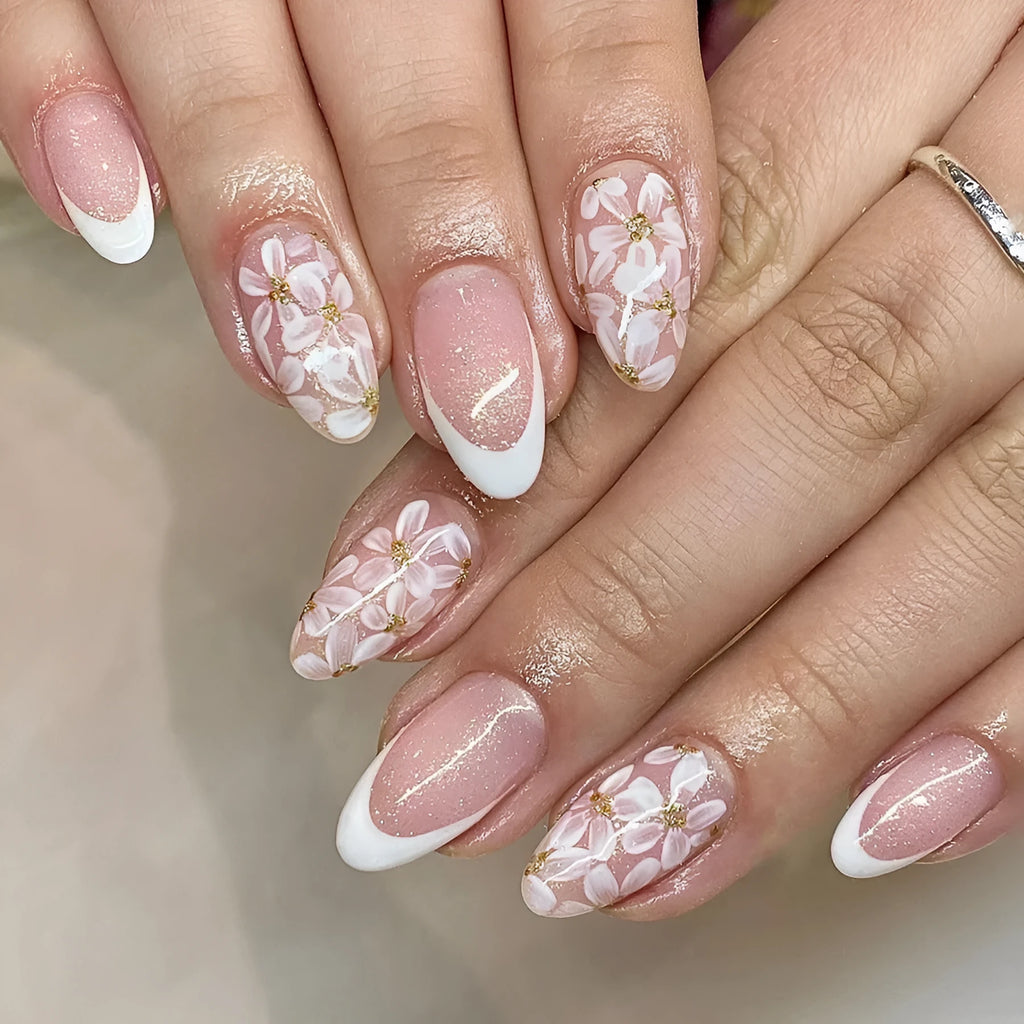 Short almond French style press-on nails with glitter accents and powder flower design on white background