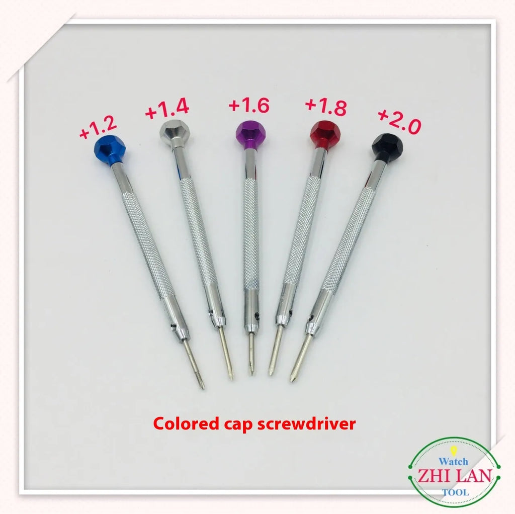 Six colour-coded watch repair screwdrivers with aluminium and copper handles laid out on a surface.