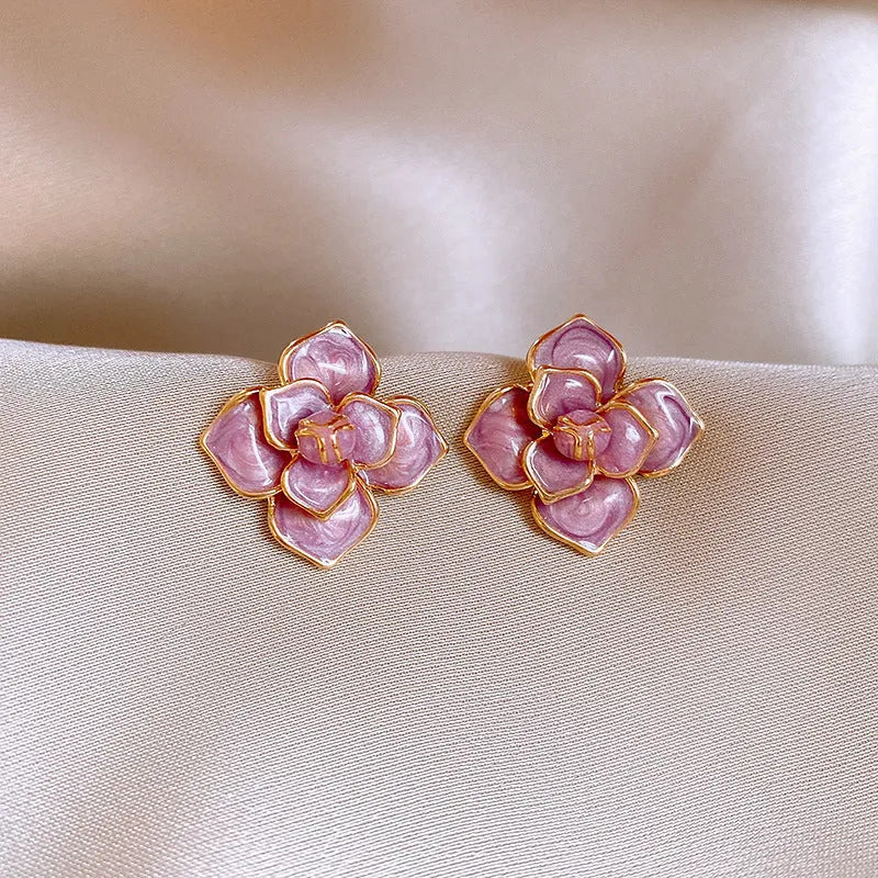 Close-up of gold plated purple oil-spot glaze flower stud earrings on a copper base.