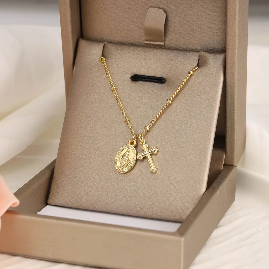 Gold geometric cross Virgin Mary pendant necklace on a chain.