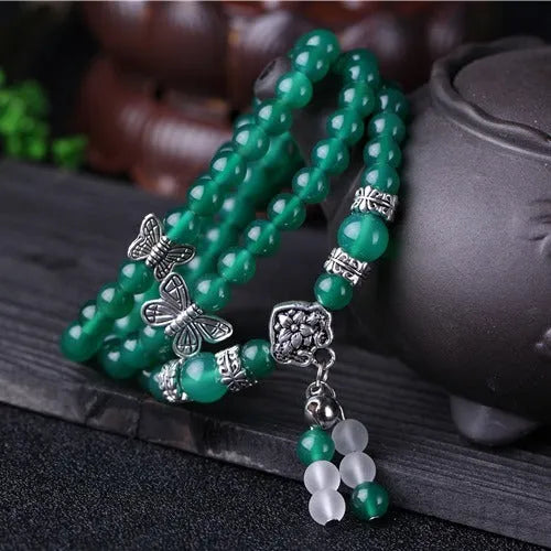 Close-up of a women's multi-strand bracelet with green agate beads on a wrist.