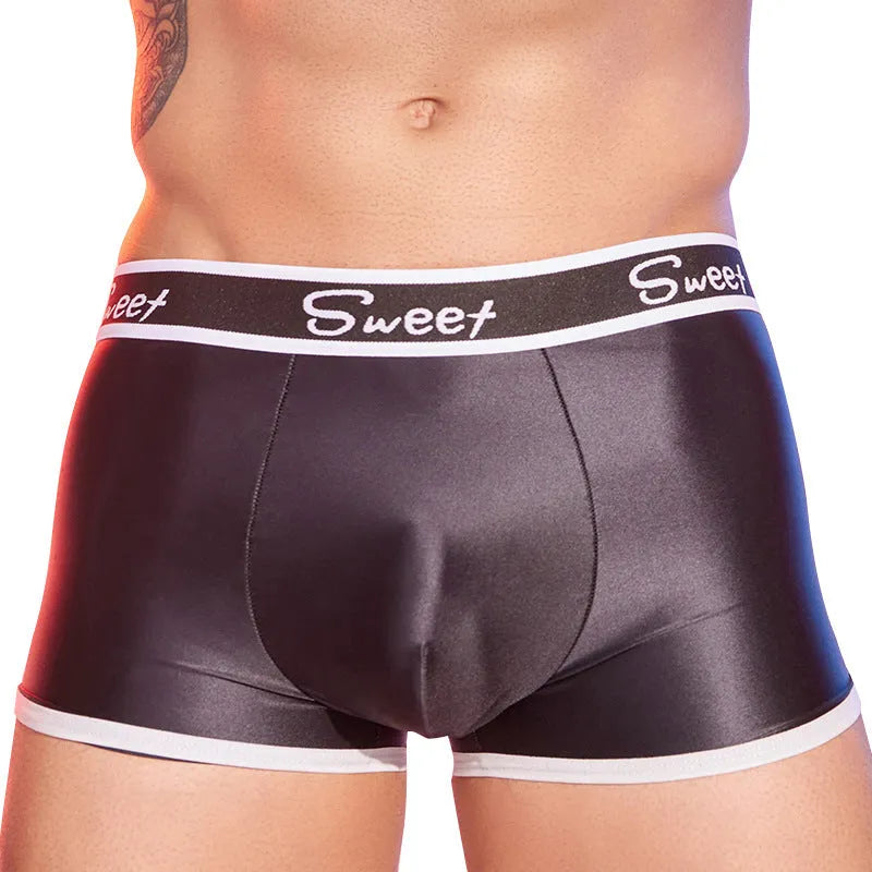 Men's shiny silky nylon boxer shorts in black, sapphire blue, and white colours on a grey background.